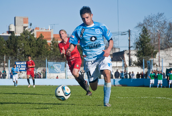 Adrián Martínez una de las figuras de CADU avanza con el balón perseguido por Carlos Madeo de Laferrere. El "celeste" volvió al triunfo. Fotos: Florencia Lapegüe.